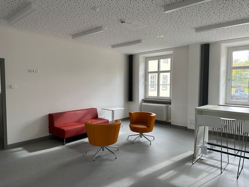 Modernisierter Aufenthaltsraum in Ellwangen mit schallabsorbierender Decke, bequemer Sitzecke und hellem, offenem Design.