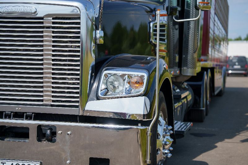 Black heavy-duty semi truck parked outdoors with chrome grille, polished wheels, and trailer attached at commercial trucking facility.