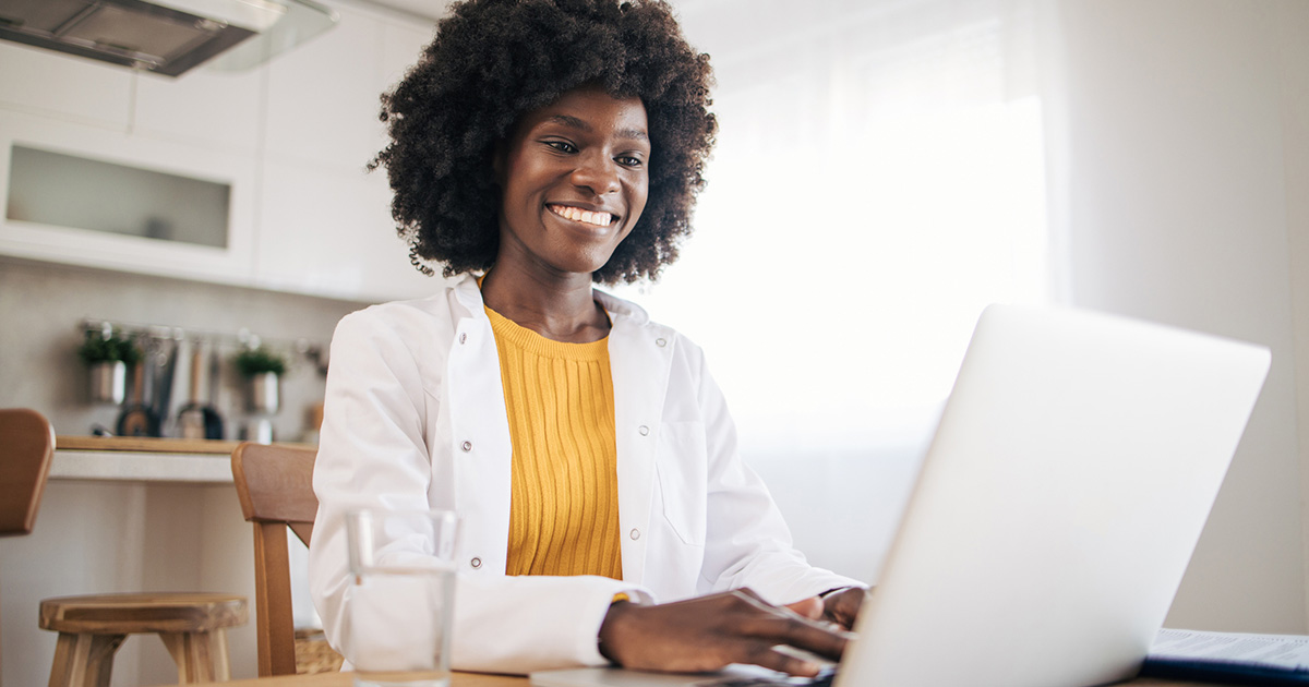 woman in lab coat at work on laptop