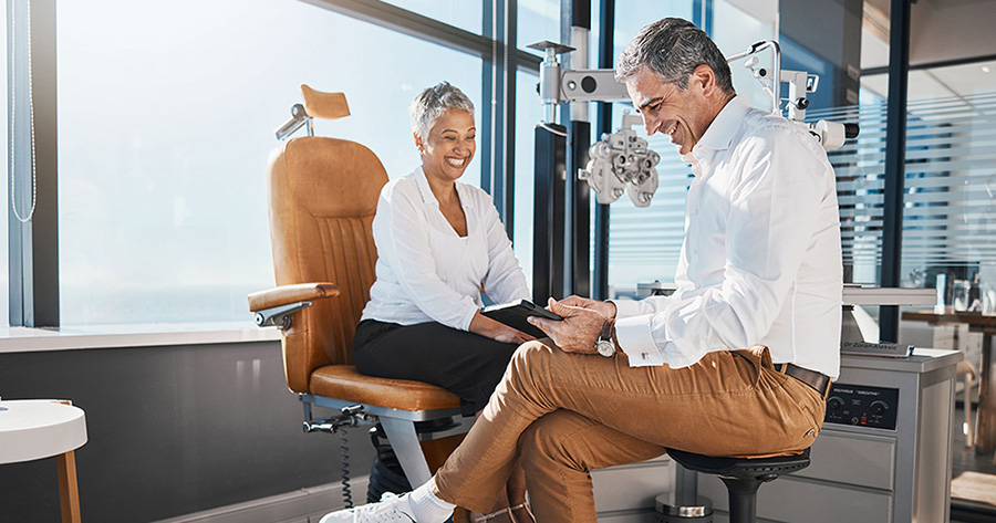 optometrist using tablet chairside with patient for eye exam