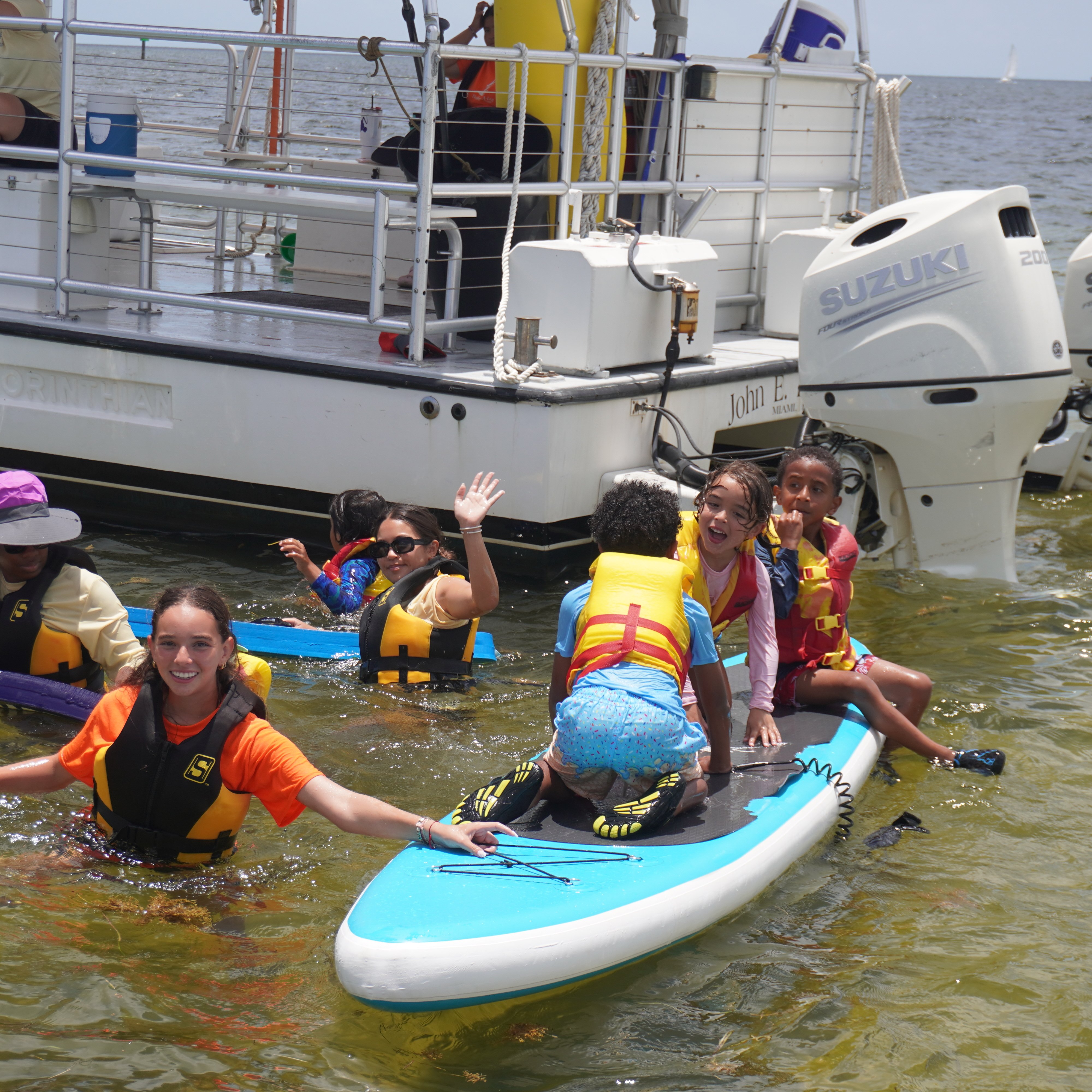 Kids on paddleboards beside the programme boat