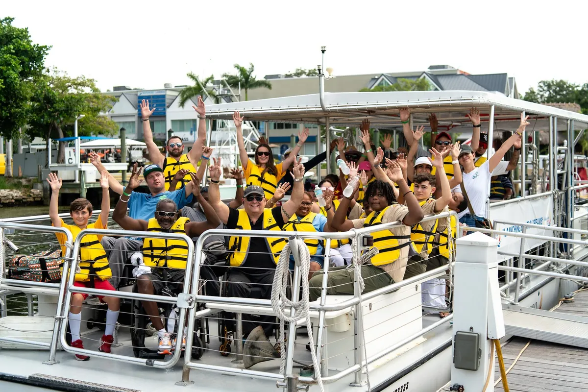 A cheering group in life vests aboard the accessible pontoon boat