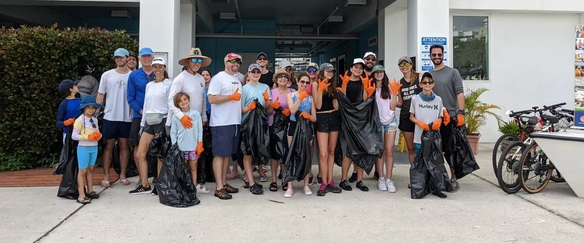 A group of volunteers holding bags of collected trash after a clean-up