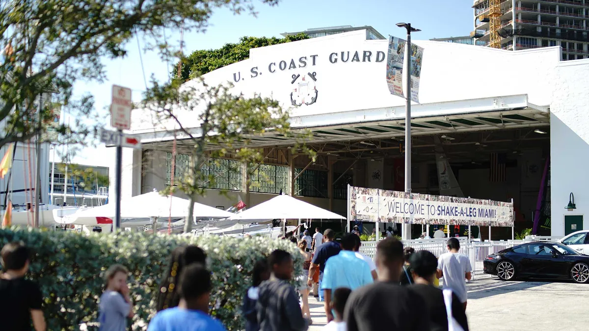 Visitors walk toward the white U.S. Coast Guard hangar, where a banner reads Welcome to Shake-A-Leg Miami