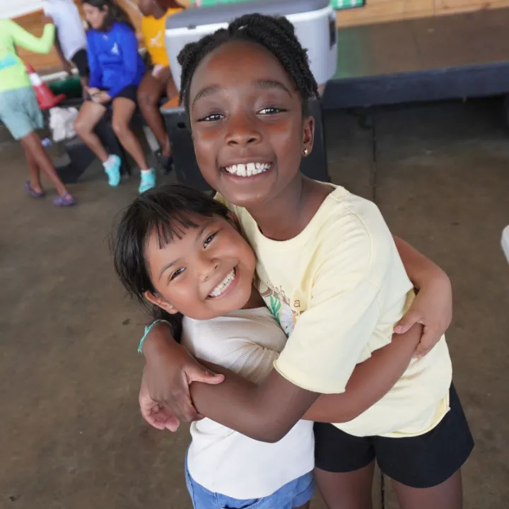Two campers hug and smile at the camera