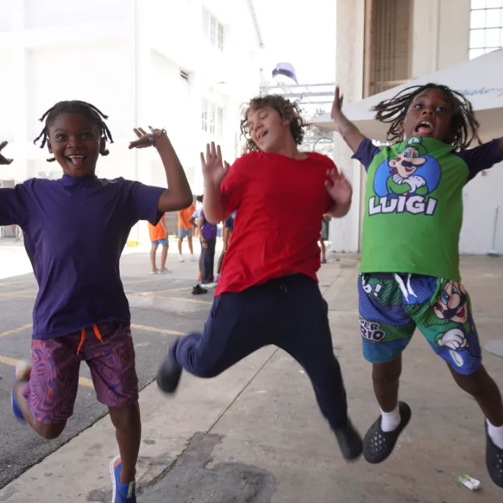 Three campers jump in the air at camp