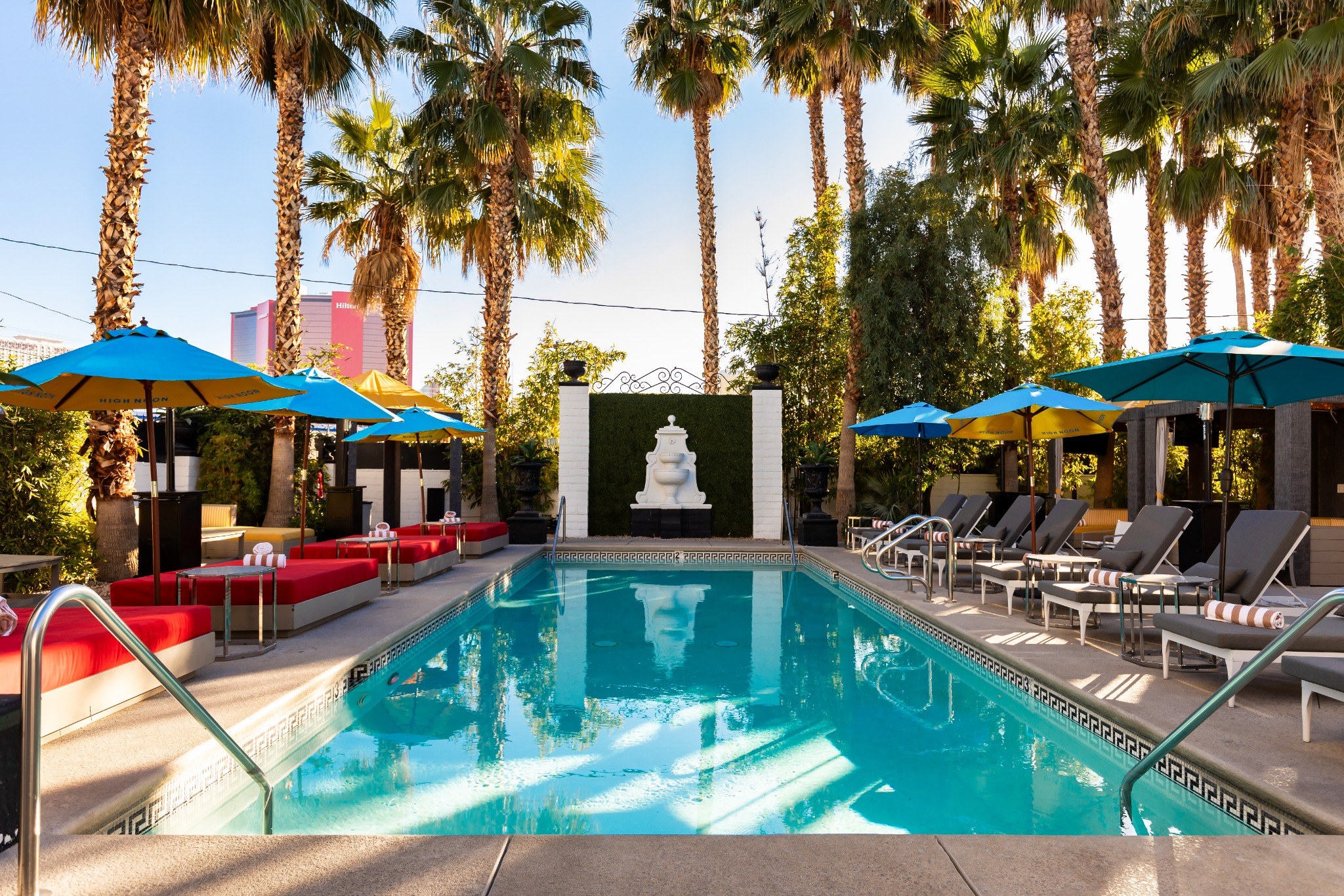 The Lexi pool with palms, loungers and red daybeds