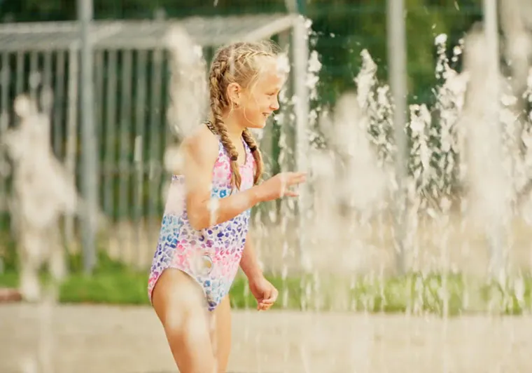 Ein Mädchen spielt in einer Wasserfontäne