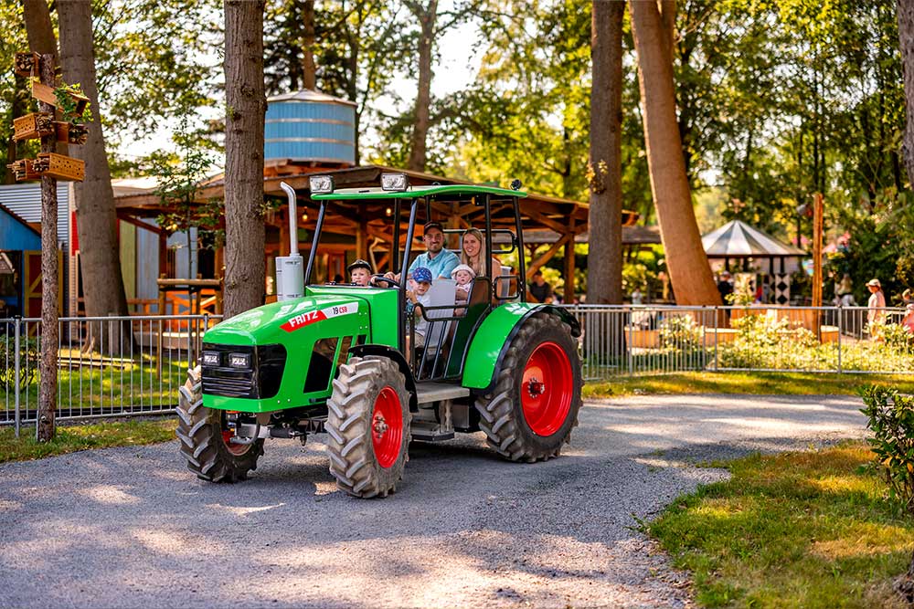 Eine Familie sitzt in einem Trecker und fährt durch einen Wald