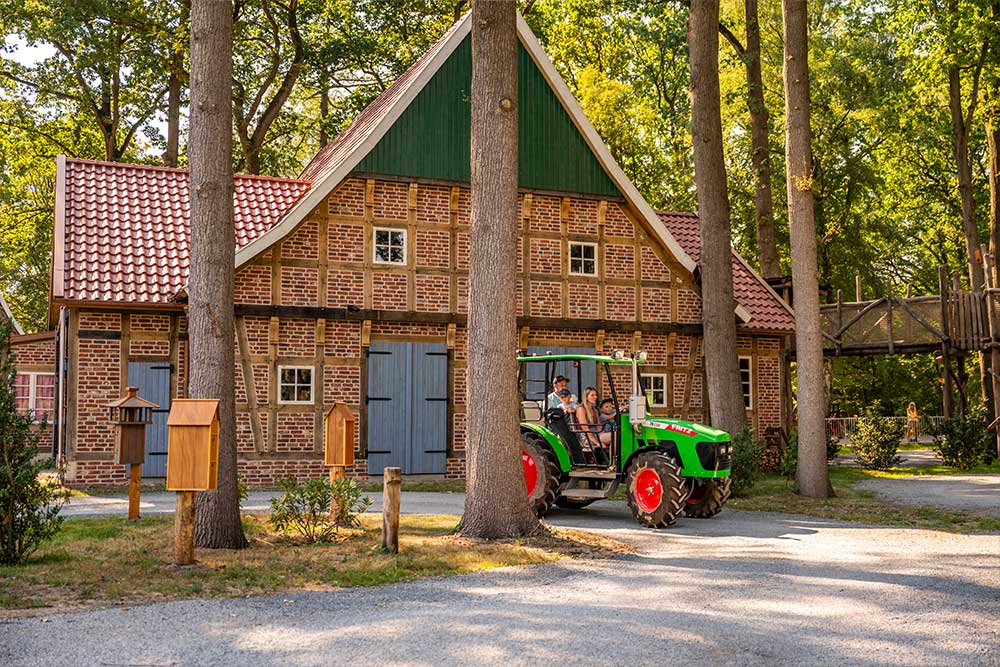 Eine Familie sitzt in einem Trecker und fährt durch einen Wald