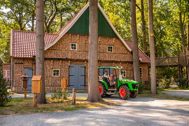 Eine Familie sitzt in einem Trecker und fährt durch einen Wald