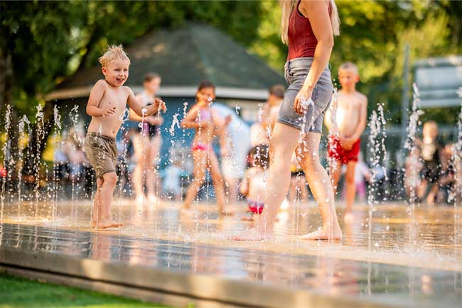 Kinder spielen in einer Wasserfontäne