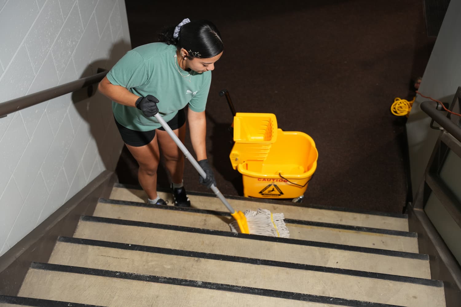 Top Tier Environmental Services crew member mopping stairs