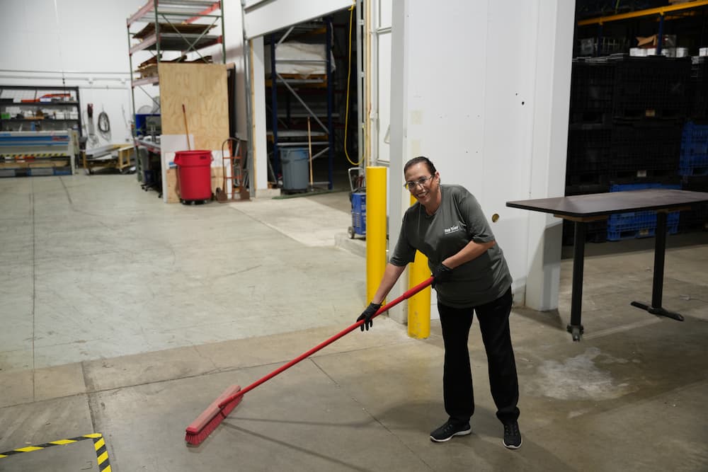 Top Tier Environmental Services crew member sweeping with push broom
