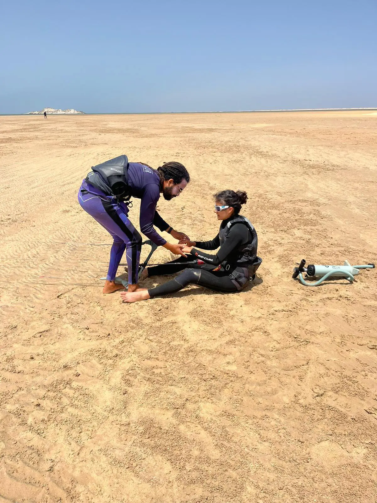 Kitesurf instructor assisting a beginner student during a lesson on the beach at Dakhla Lagoon in Morocco.