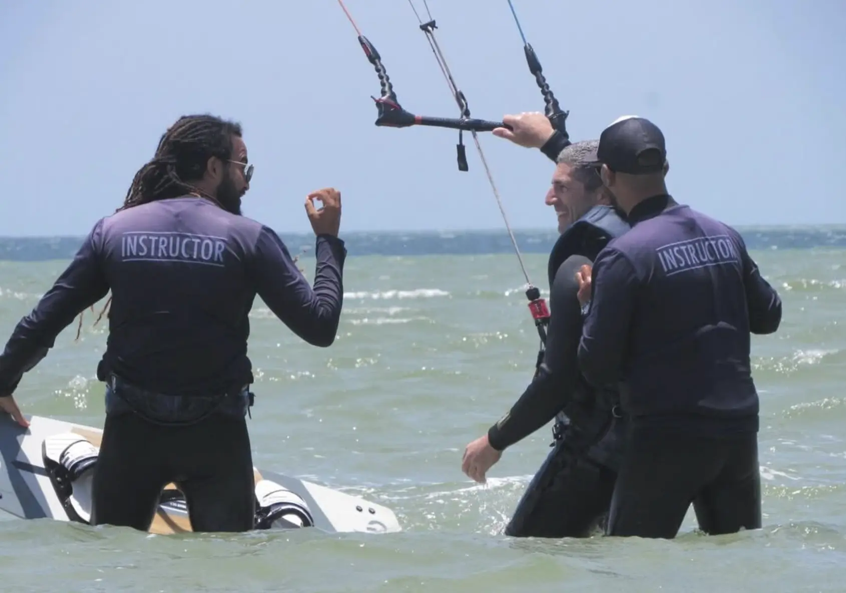 Kitesurf instructors coaching a student during a lesson in the water at Dakhla Lagoon, Morocco.