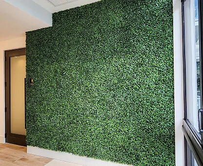 Tall accent wall covered in artificial plant wall from floor to ceiling.