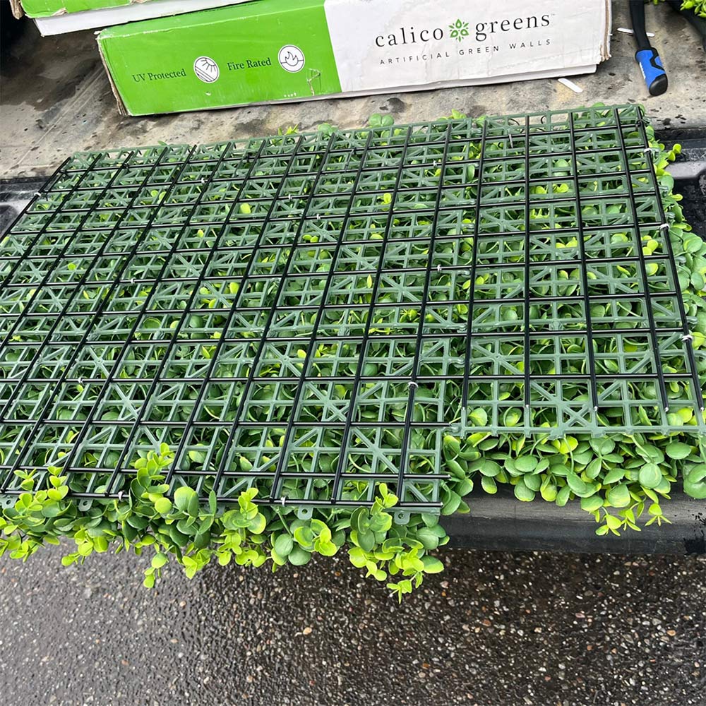 The backside of an artificial plant wall panel showing the grid structure behind the plants.