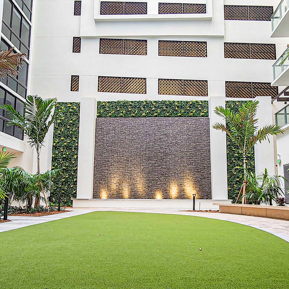 Large outdoor open area with decorative water wall and accented artificial plant wall features.