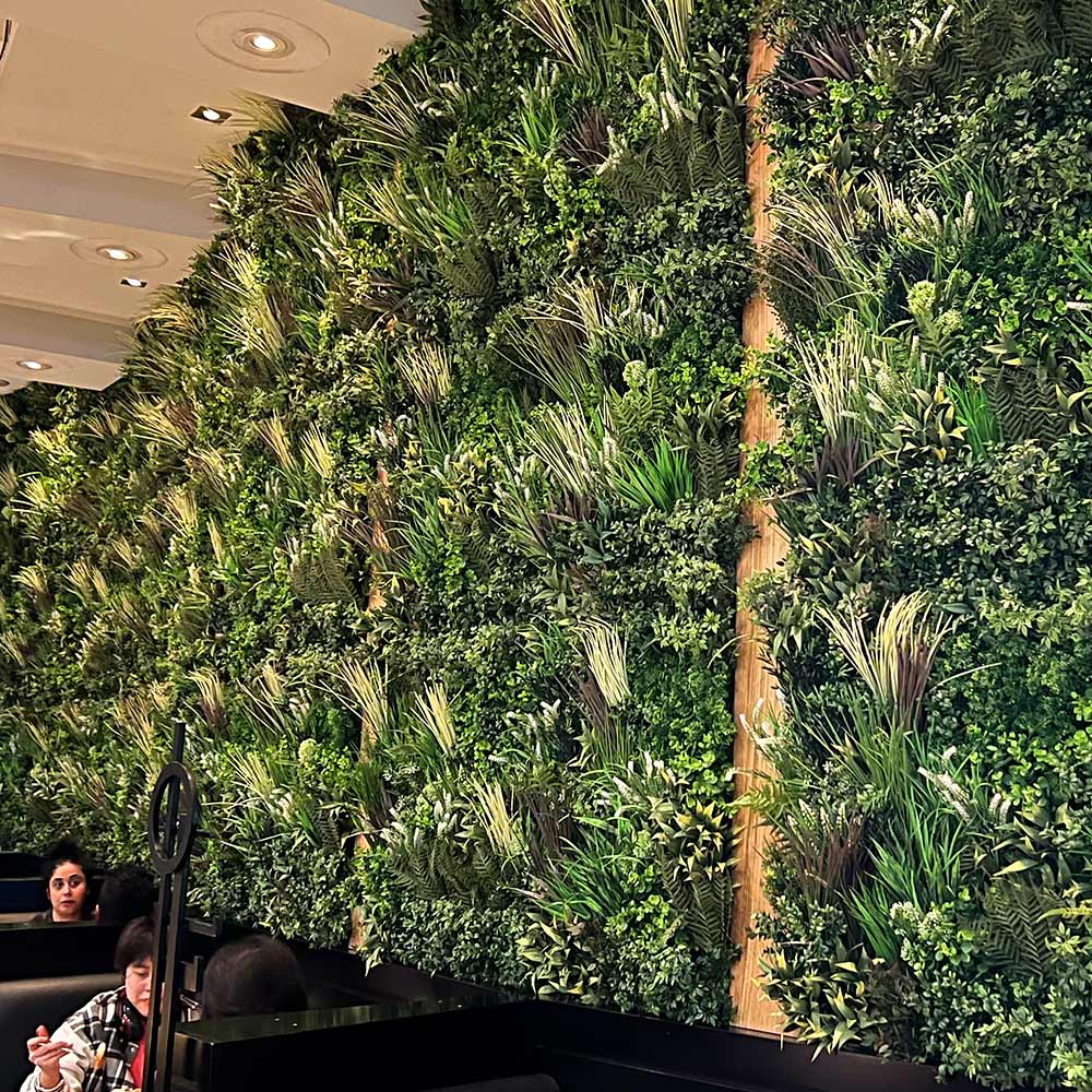 Inside walls of a commercial establishment or restaurant with artificial plant walls.