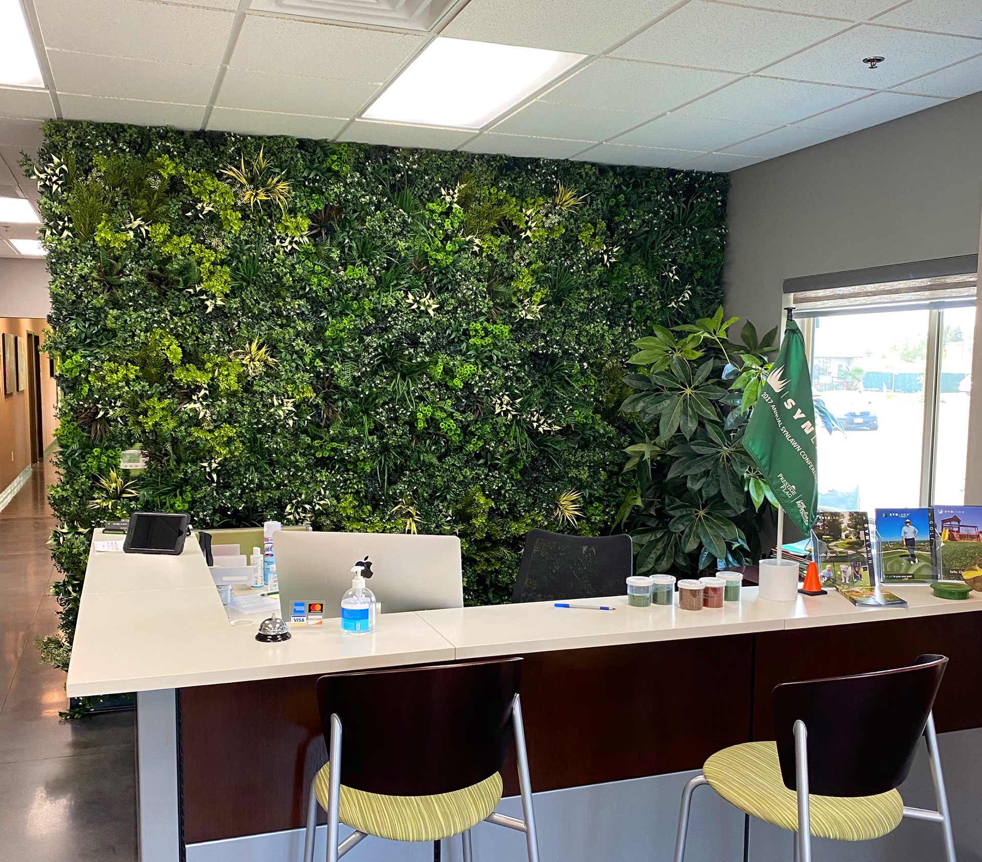 Office setting with a wall covered in artificial plant walls