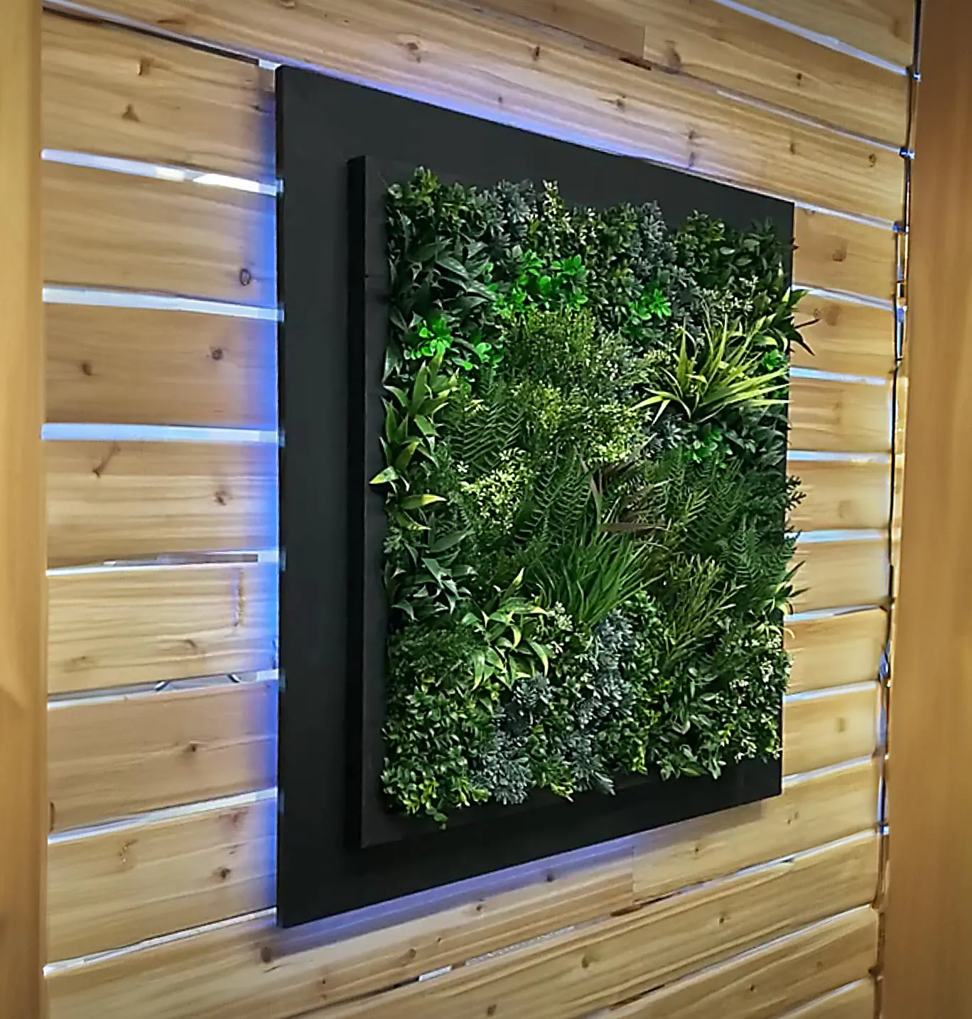 A LED backlight square with artificial turf on front of a wooden panel wall.