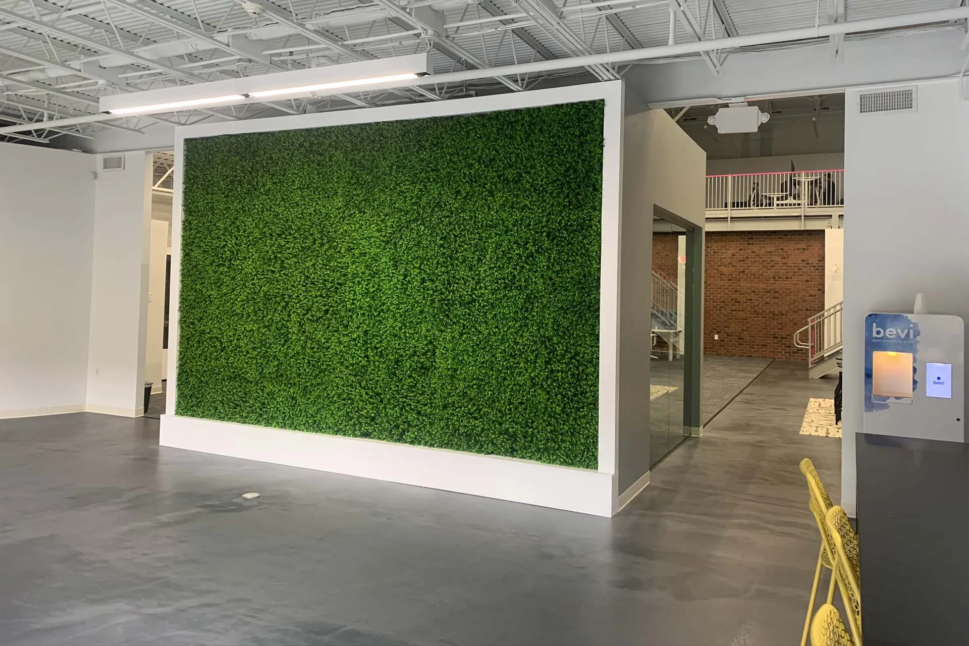 Wall in the middle of the room with artificial plants on the wall.