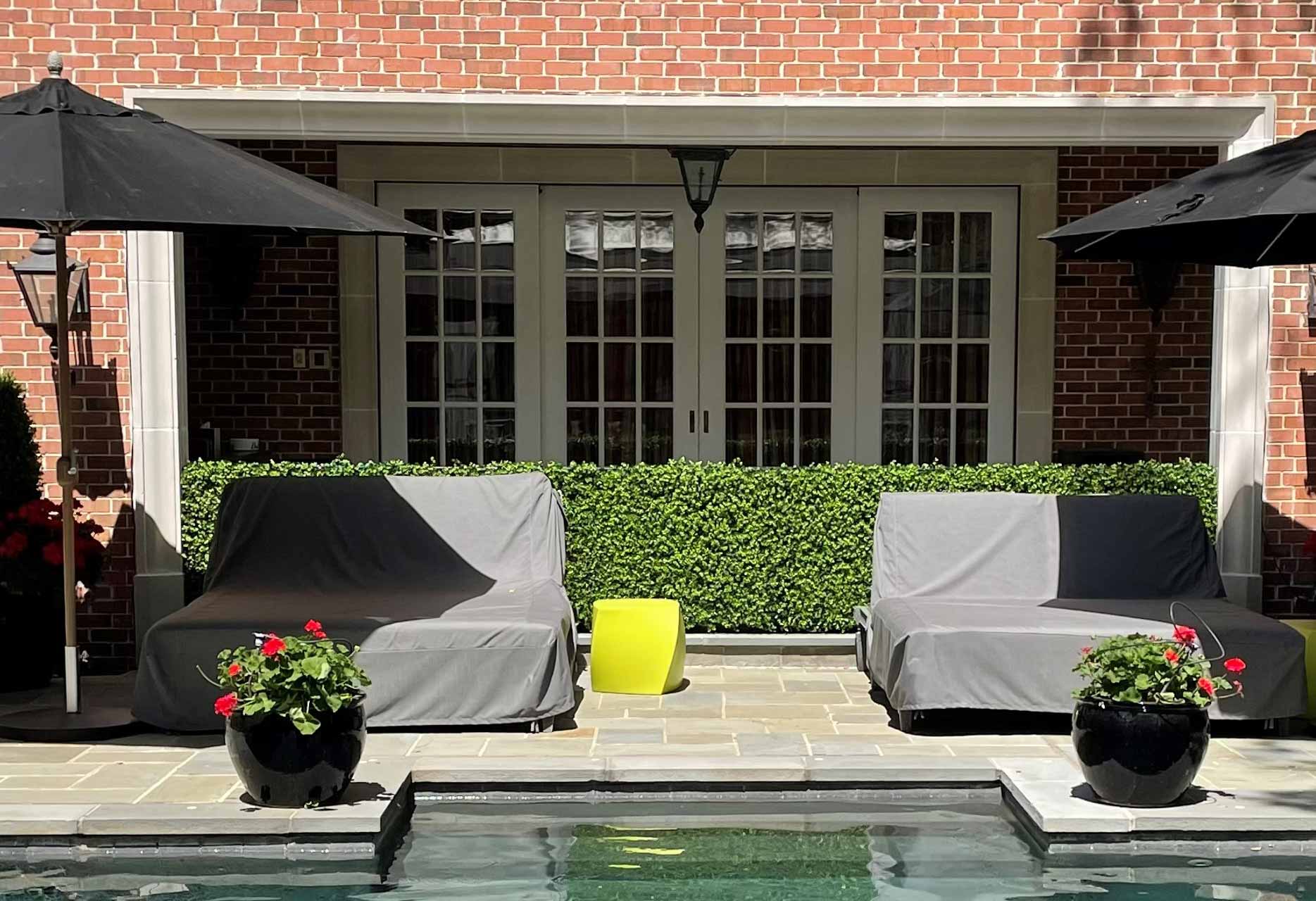 Residential backyard with a hedge made of artificial plants in a pool area