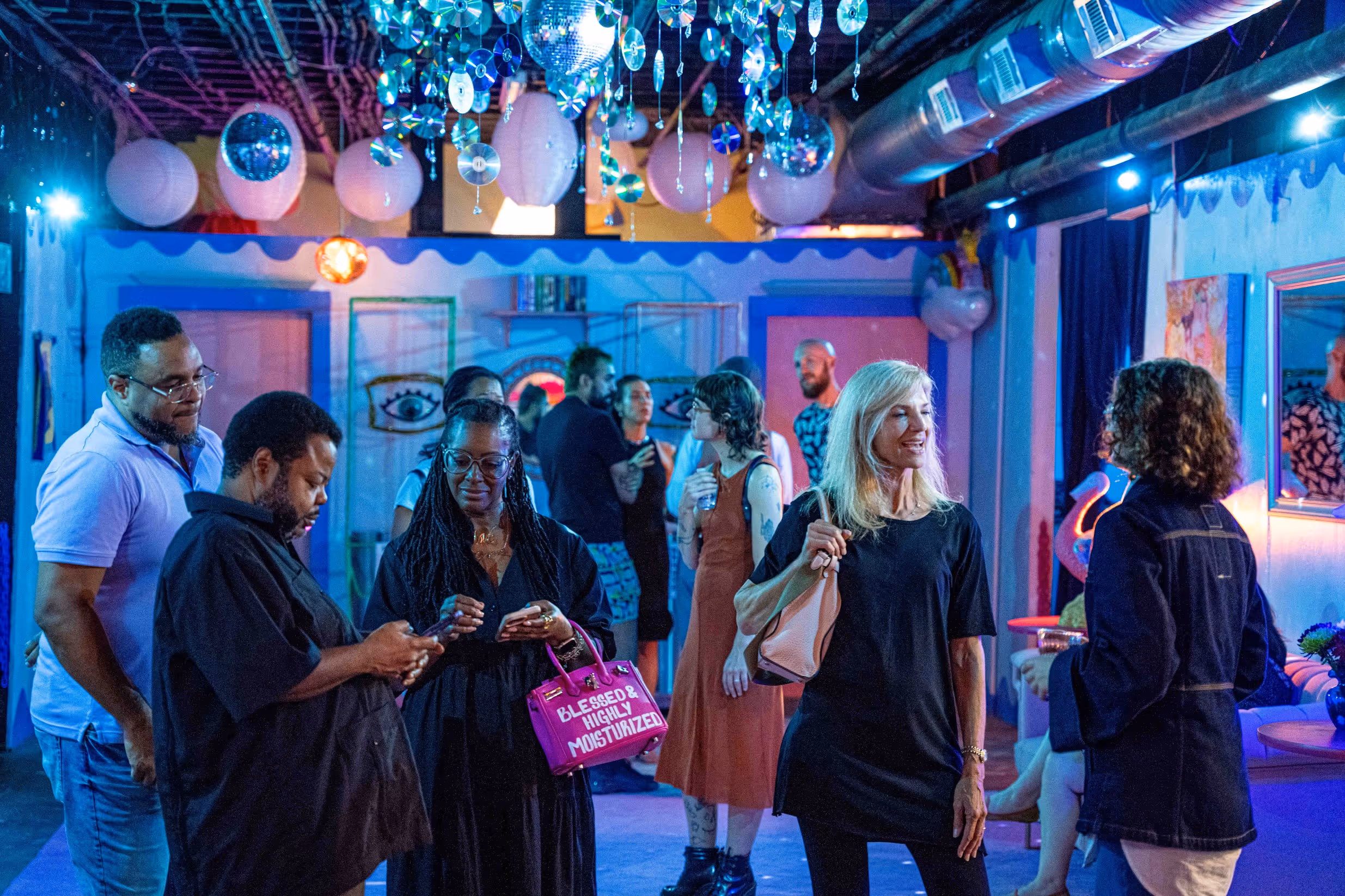 Guests mingle under hanging disco balls in The Supermarket ATL’s colorful, neon-lit venue—capturing the welcoming vibe of Staple Events.