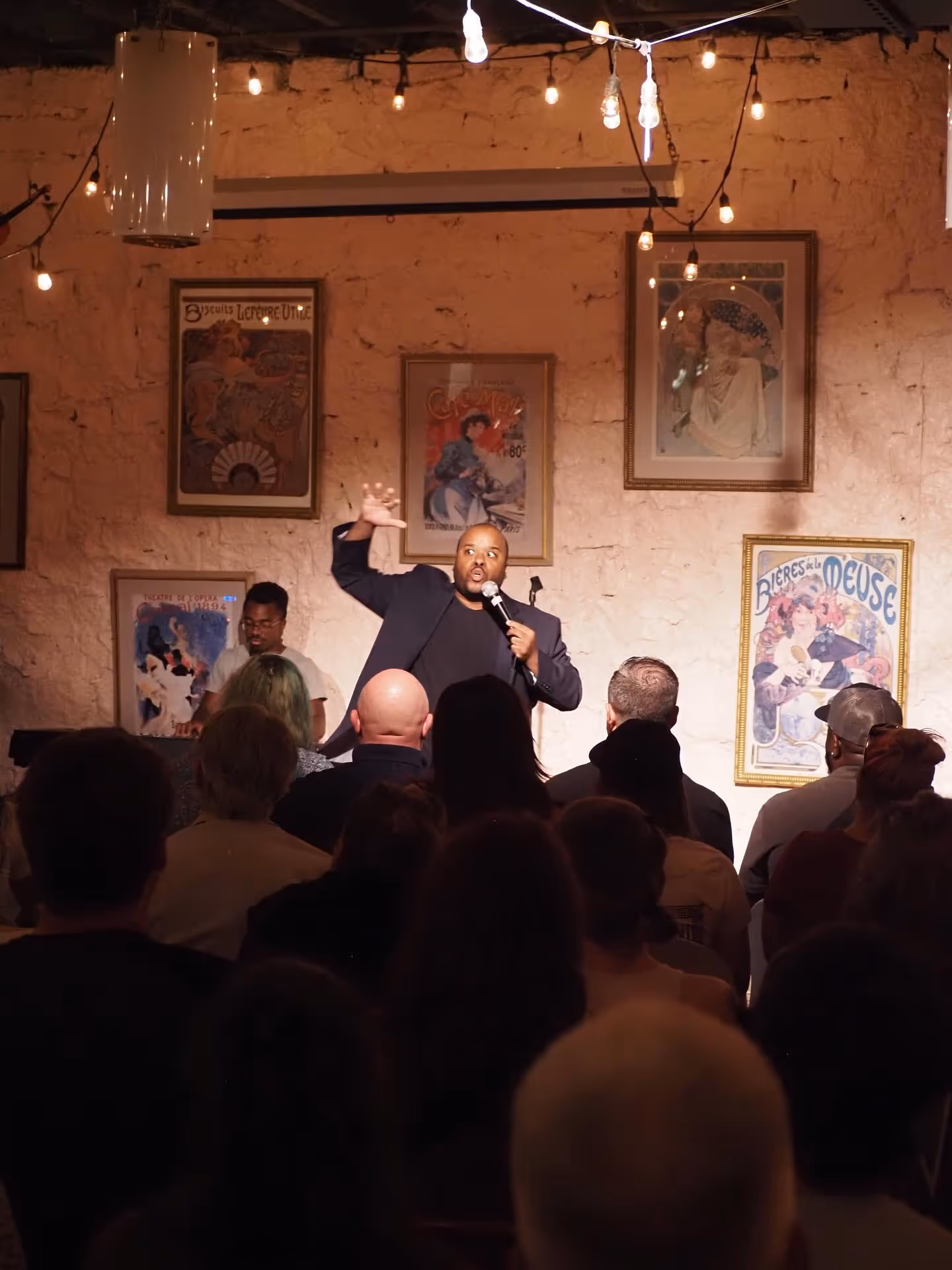 Comedian performing for a packed crowd at Secret Aisle.
