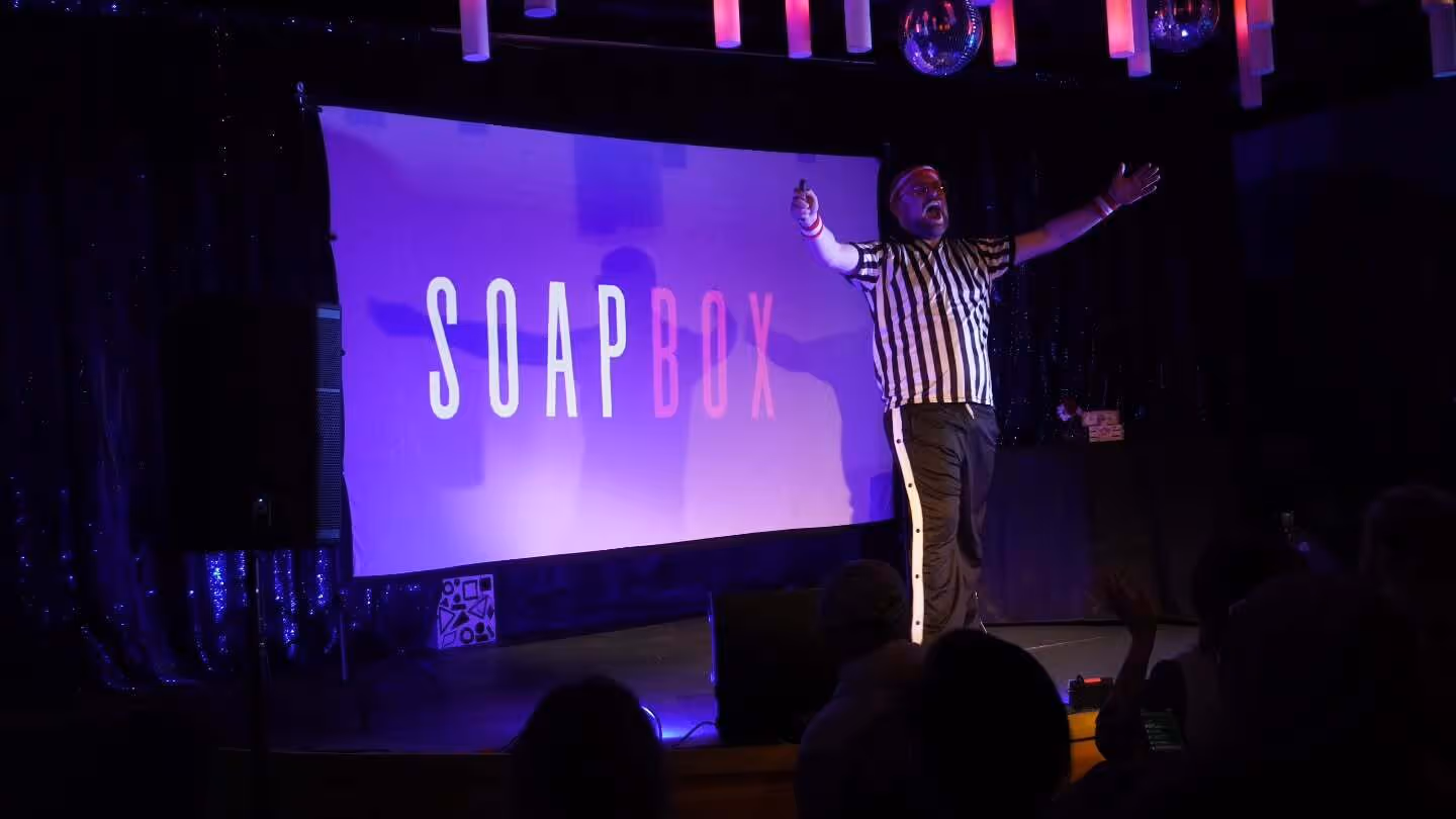 Soapbox host on stage in a referee shirt, welcoming the crowd.