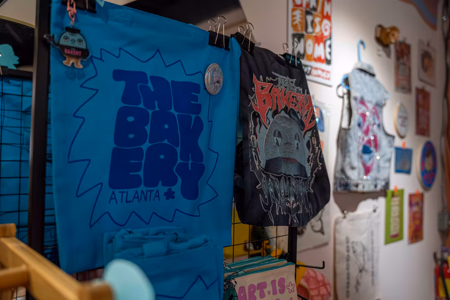Blue and black bags hanging on a rack with 'THE BAKERY ATLANTA' and cartoon graphics displayed.