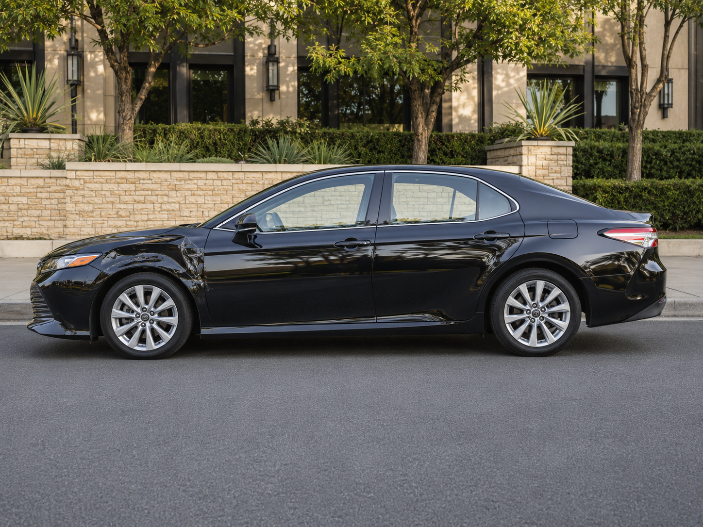 Black sedan photographed in profile at the curb.