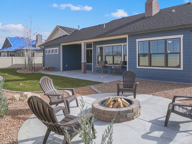 Rear exterior of a single-family home with a patio, chairs, and a fire pit.