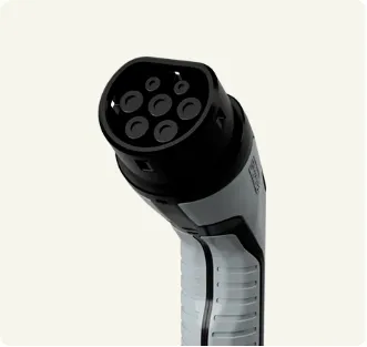 Close-up of a black and grey Type 2 electric vehicle charging plug on a light background.