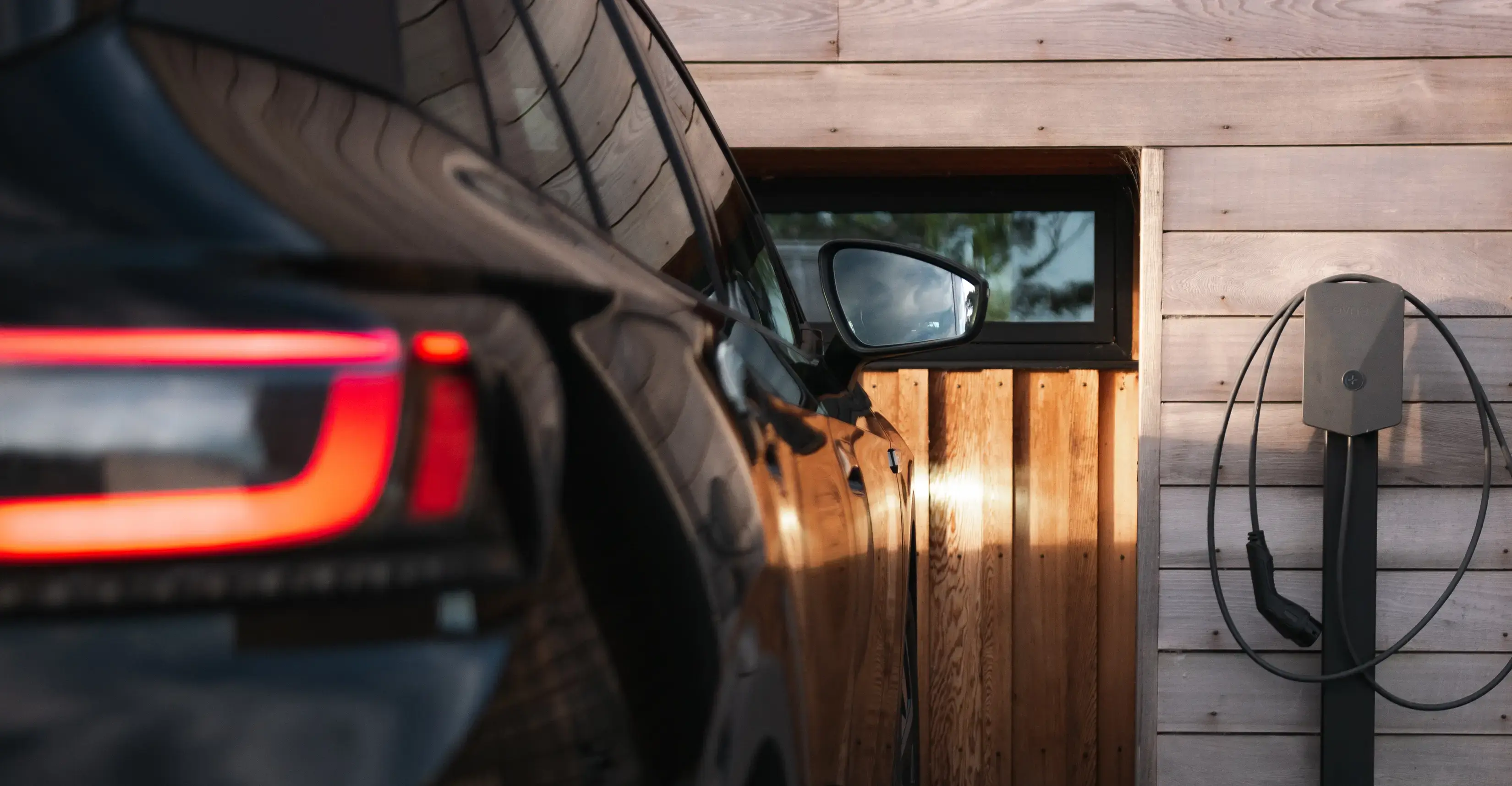 A black car parked in a driveway with an Evnex E2 range charger ready for use