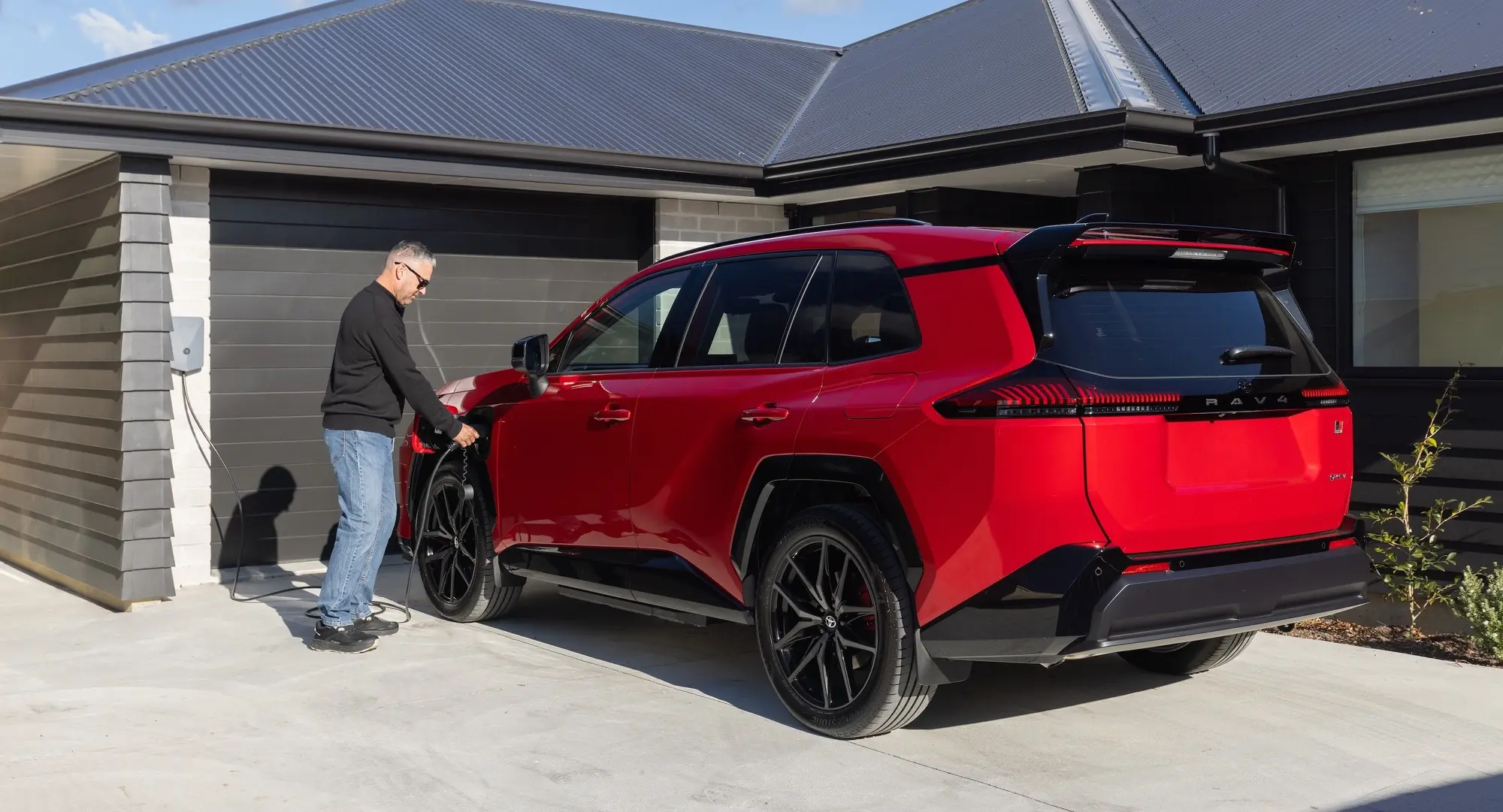 A man charges his electrified Toyota using an Evnex EV charger