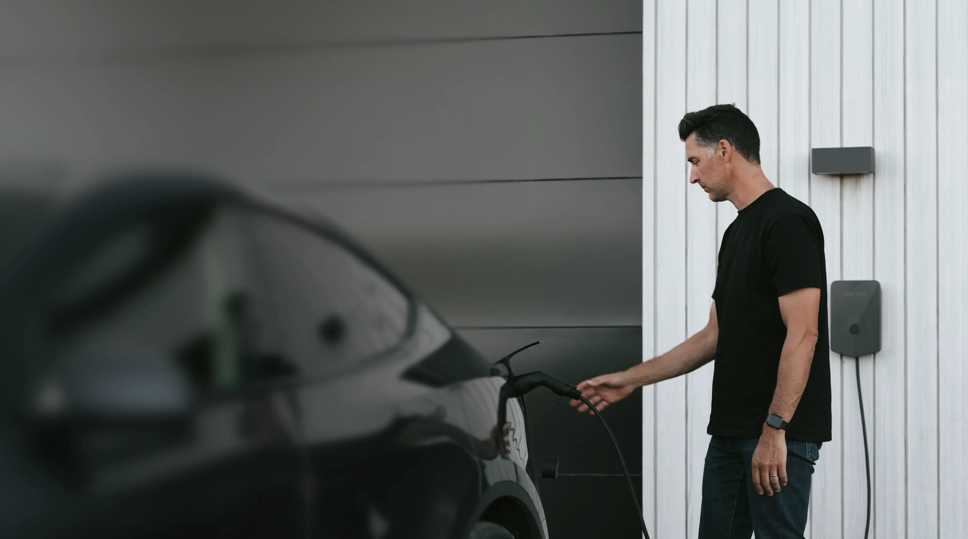 A man charges his Tesla with an Evnex EV charger