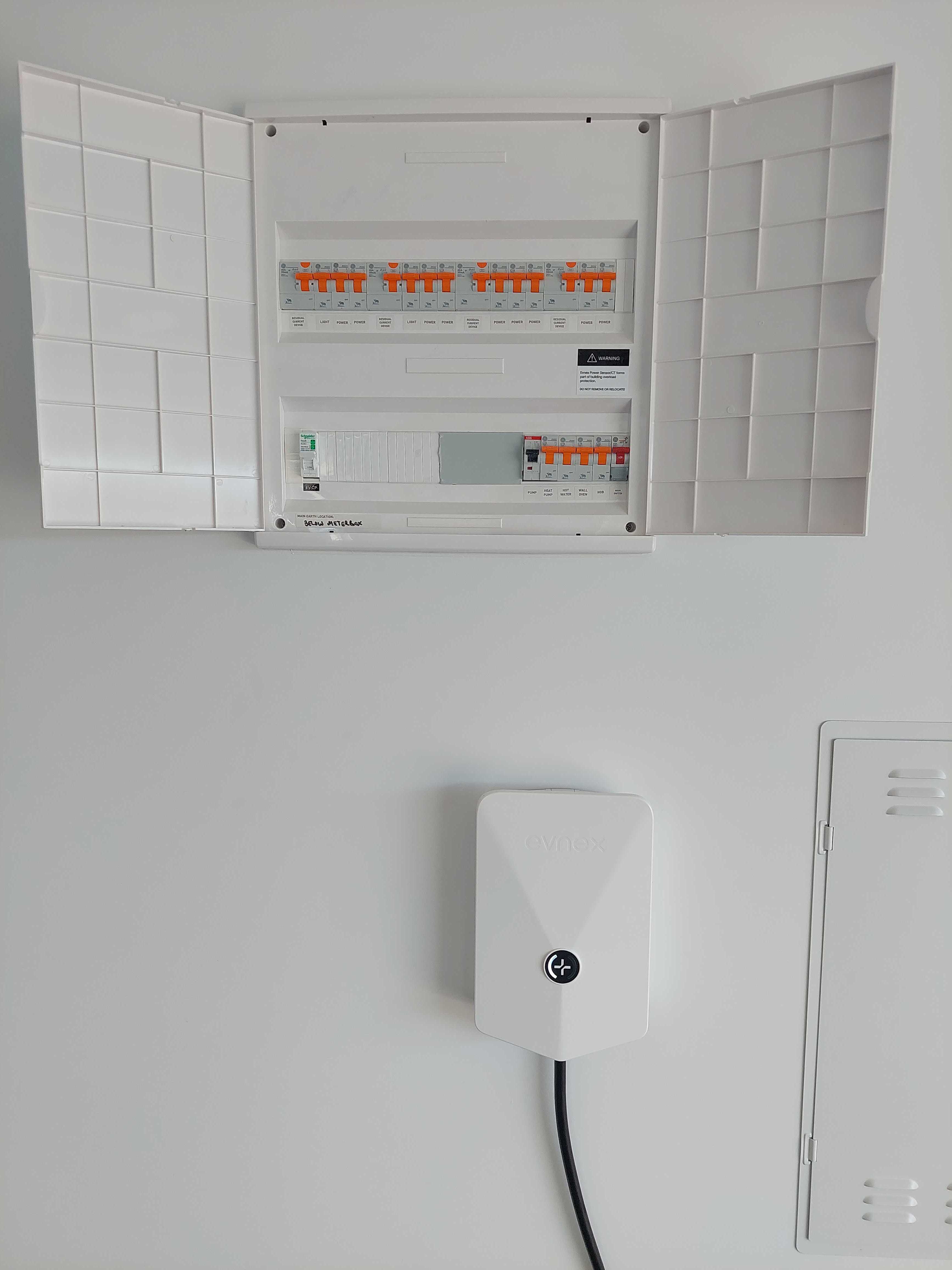 A Snow-coloured E2 Core installed directly underneath a switchboard. The wall and switchboard are both white. The switchboard has orange levers.