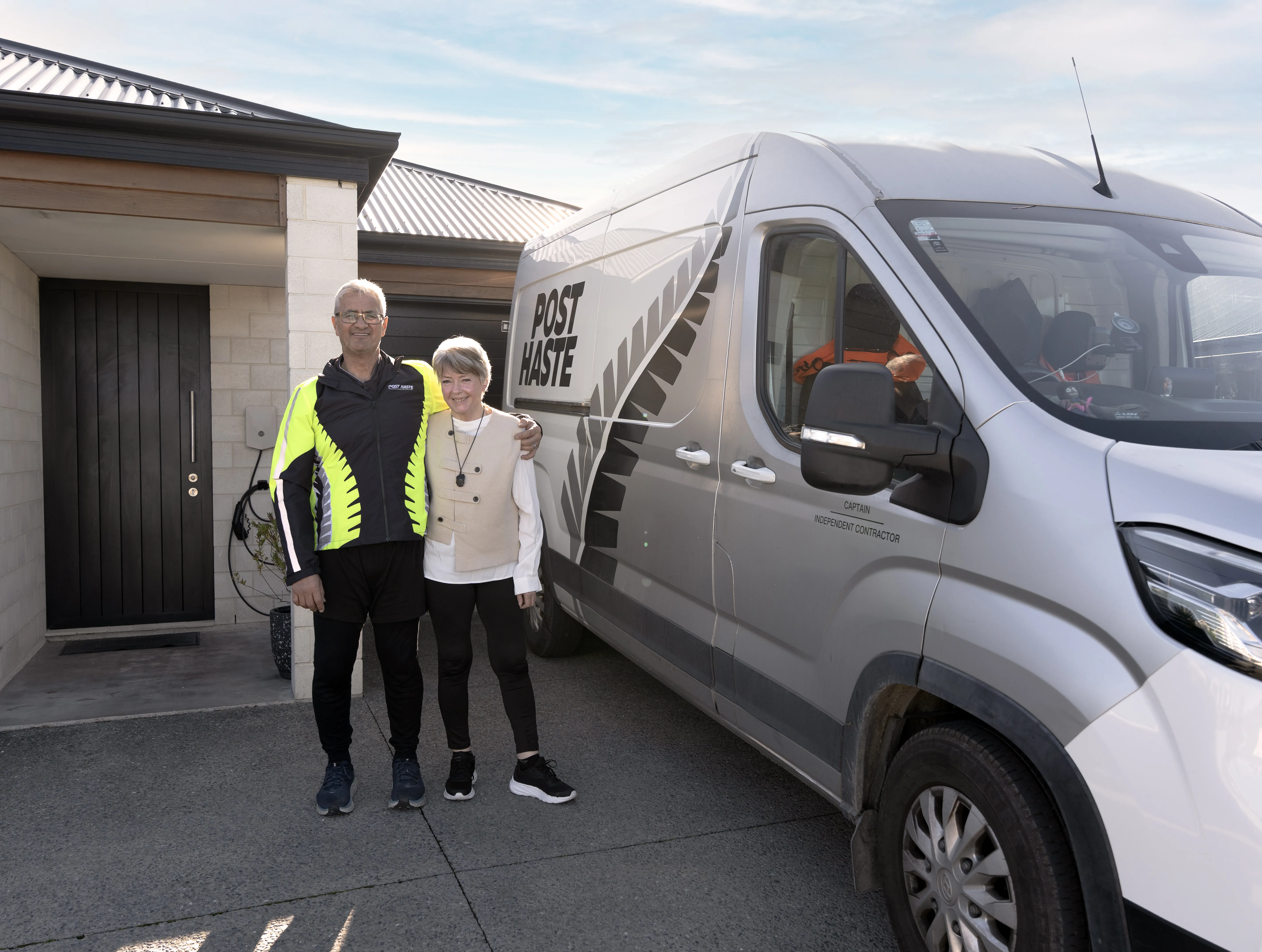 The Tua's in front of their electric Courier van and Evnex home EV charger