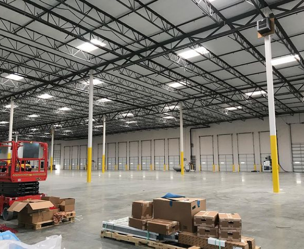 A warehouse with neatly stacked boxes and a forklift parked nearby.