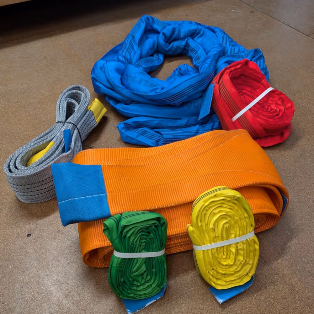 Collection of heavy-duty synthetic lifting slings in various colors and sizes, including flat web and round slings