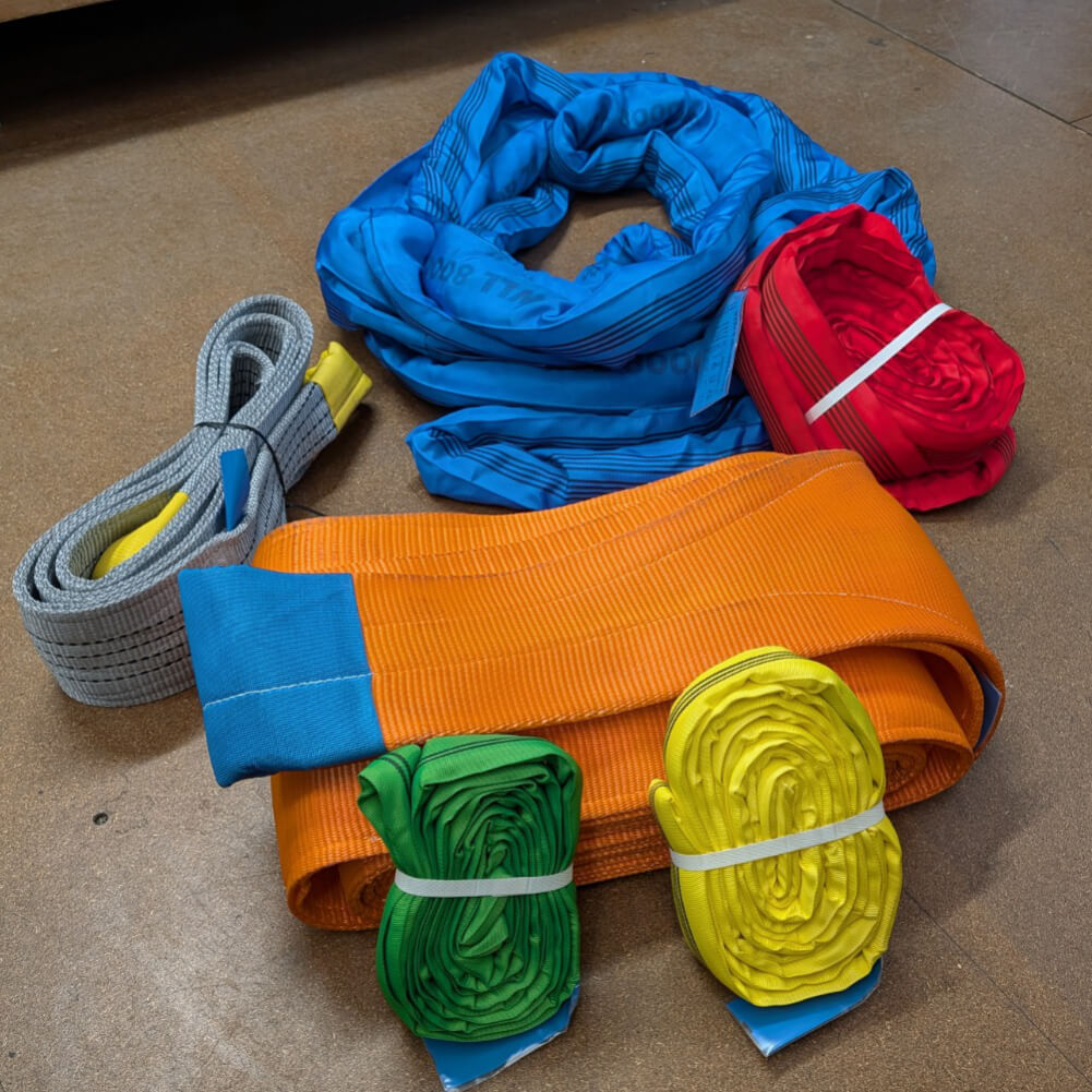 Collection of heavy-duty synthetic lifting slings in various colors and sizes, including flat web and round slings