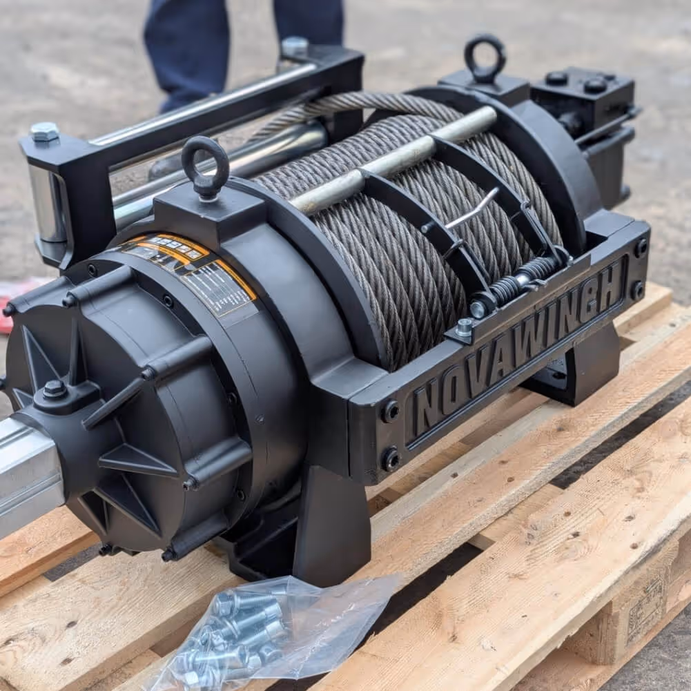 A robust black Novawinch brand hydraulic winch featuring a neatly spooled steel cable, resting on a wooden shipping pallet