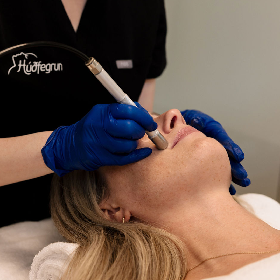 Hjúkrunarfræðingur Húðfegrunar framkvæmir Microdermabrasion meðferð í björtum og fallegum aðstæðum. Bókaðu tíma hjá leiðandi húðstofu Reykjavíkur með nýjustu tækni í húðmeðferðum.
