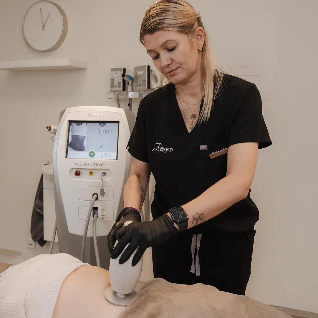 Sjúkraliði á Hudfegrun framkvæmir fitueyðandi ómskoðunarmeðferð (ultrasound fat reduction) á kvið skjólstæðings í björtum og nútímalegum aðstöðu stofunnar. Meðferðin notar nýjustu tækni til að brjóta niður fitu í fitufrumum, sem umbreytist í vatn og skiljast náttúrulega úr líkamanum. Skjólstæðingurinn liggur afslappaður á meðferðarbekk á meðan tækið er dregið markvisst yfir meðferðarsvæðið. Hudfegrun mælir með fjórum til sex meðferðum til að ná sem bestum og varanlegum árangri í líkamsmótun.