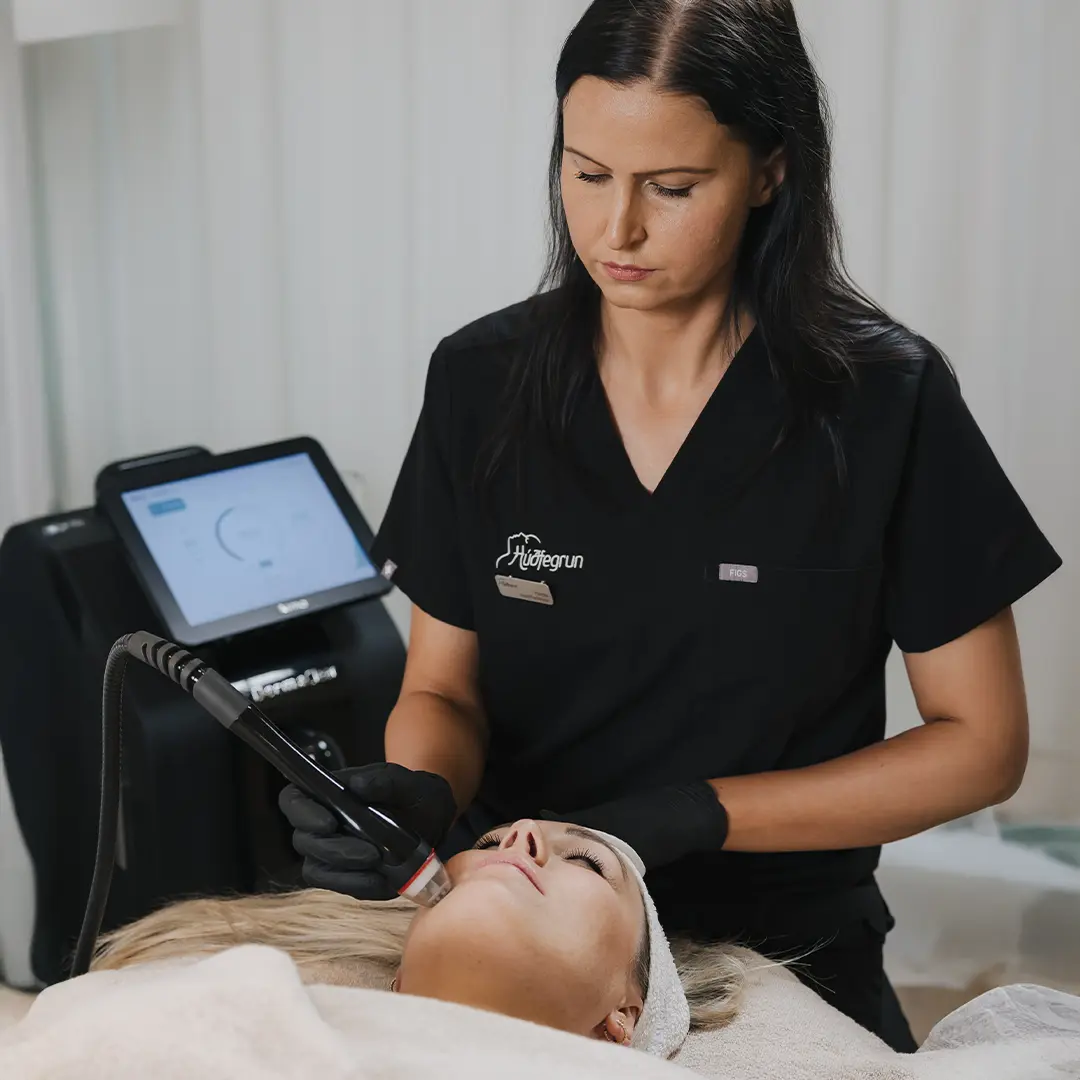 Hjúkrunarfræðingur hjá Hudfegrun framkvæmir Dermaclear-húðmeðferð á skjólstæðingi í björtum og hreinum aðstæðum kliníkurinnar. Myndin sýnir notkun háþróaðrar Dermaclear-tækni til djúphreinsunar og endurnýjunar húðar með faglegri framkvæmd.