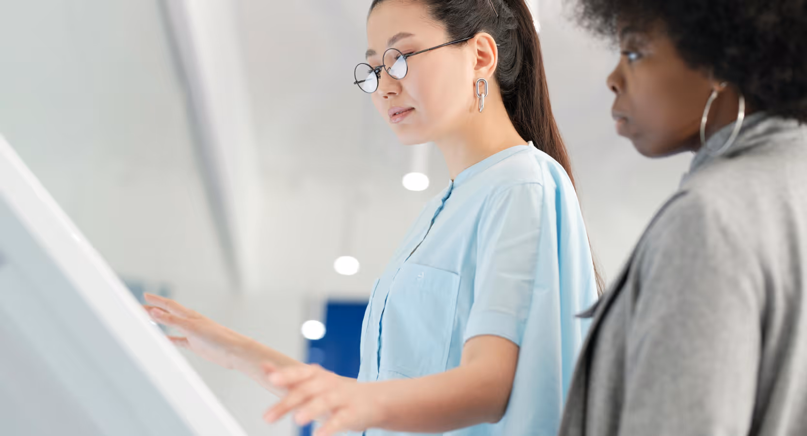 two professionals in front of a big screen, discussing product design features during a workshop meeting