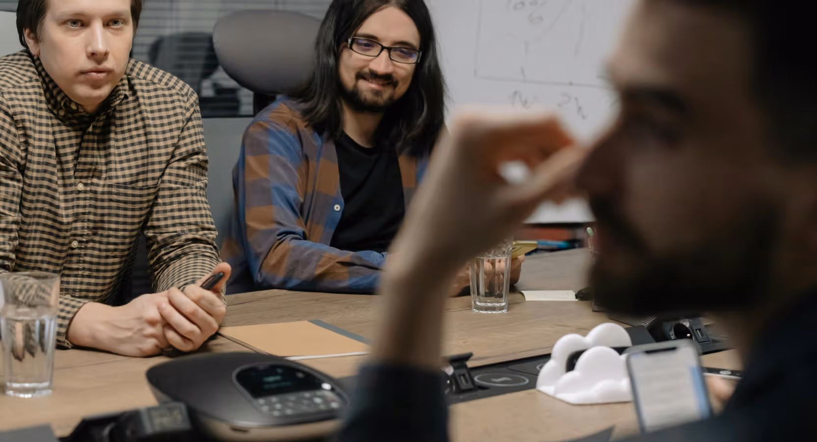 Two team members engaged in a collaborative discussion during a HealthTech project planning session, with conference call equipment visible on the table
