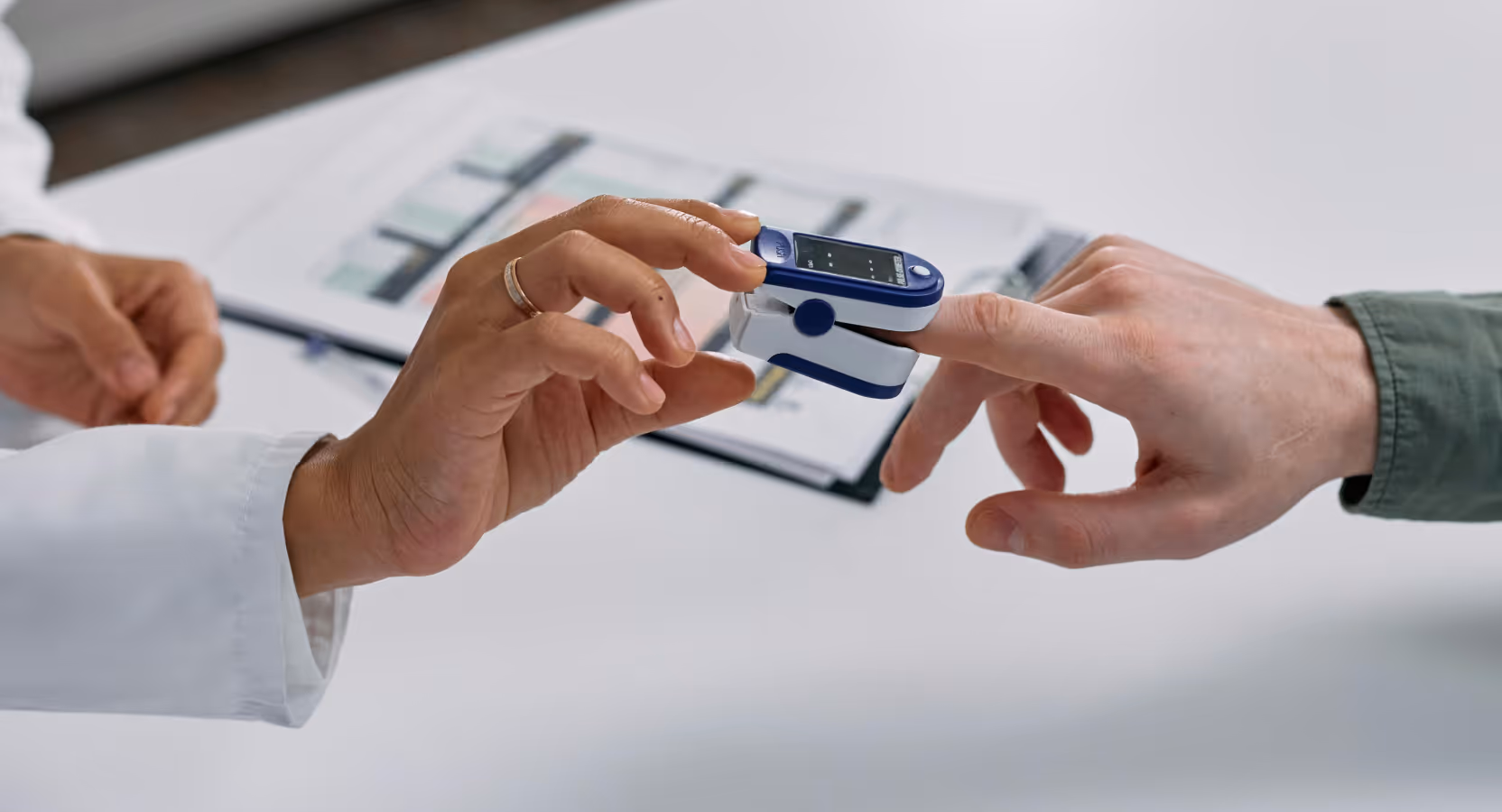 Close-up of a healthcare professional placing a pulse oximeter on a patient’s finger, demonstrating remote patient monitoring technology in modern healthcare. Example of AI-powered digital health solutions improving patient care, developed by Momentum.